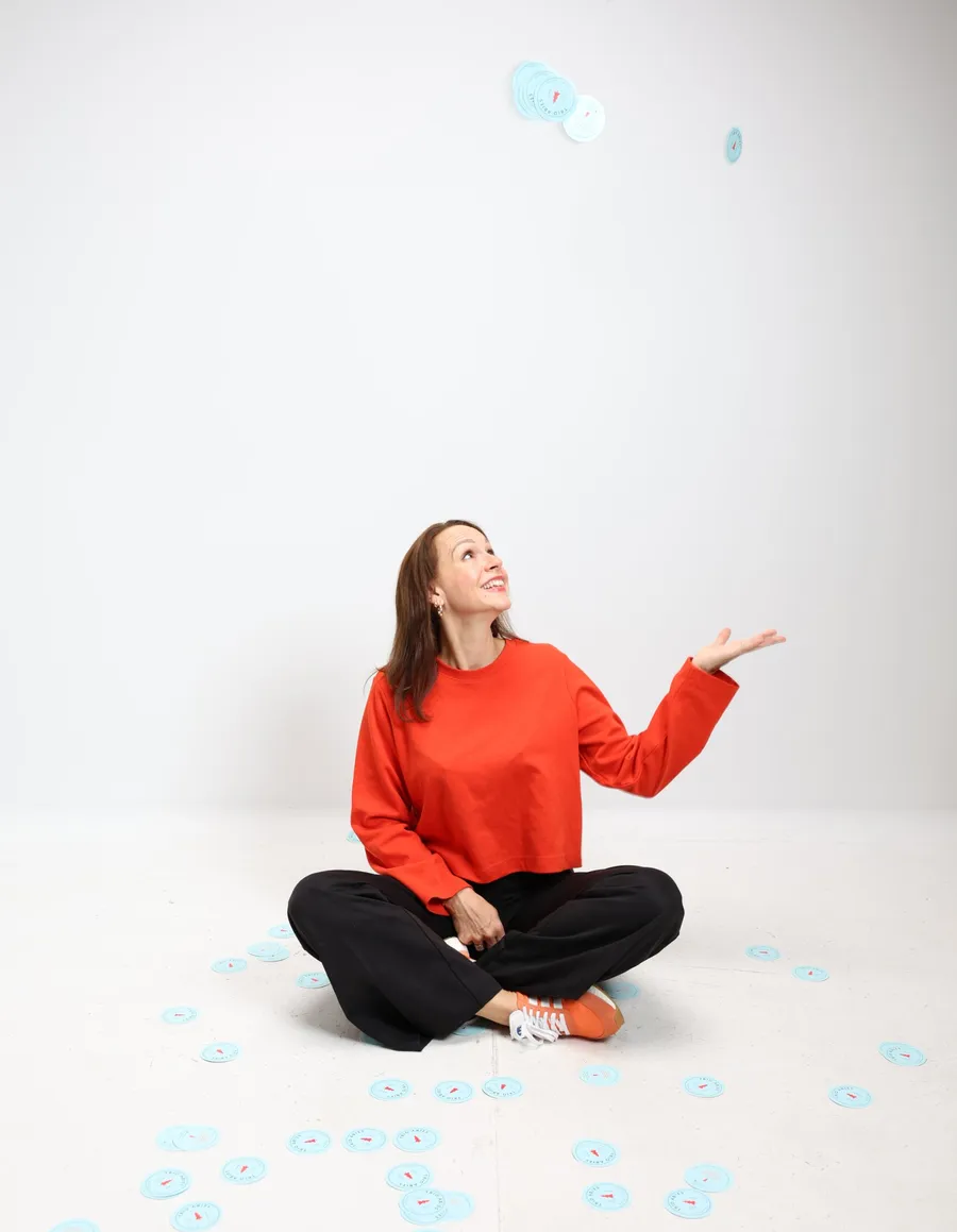Marina Laurent, assise en tailleur, lance des macarons en l’air