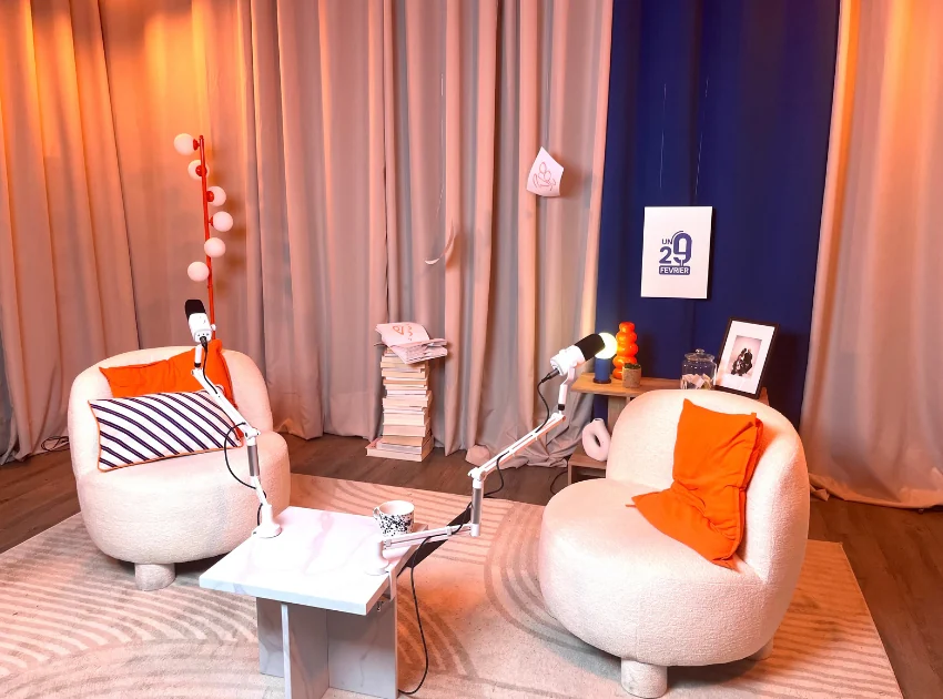 Photo du studio de podcast installé : deux fauteuils bouclés, table basse en marbre et rideaux